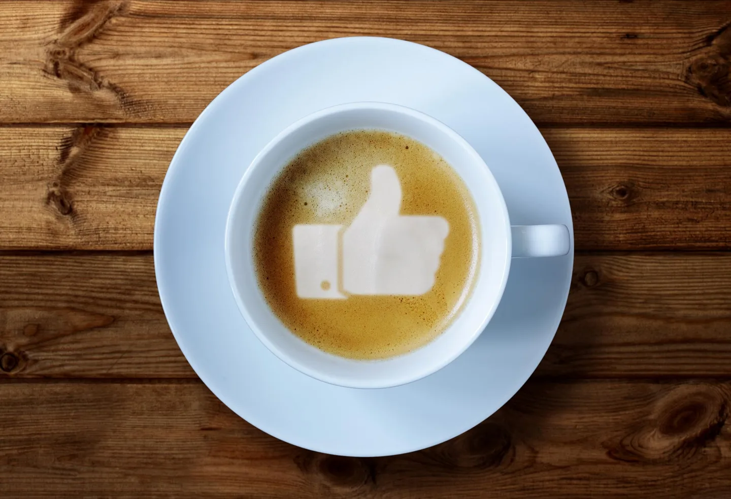 A coffee cup with a thumbs-up symbol in the milk foam.