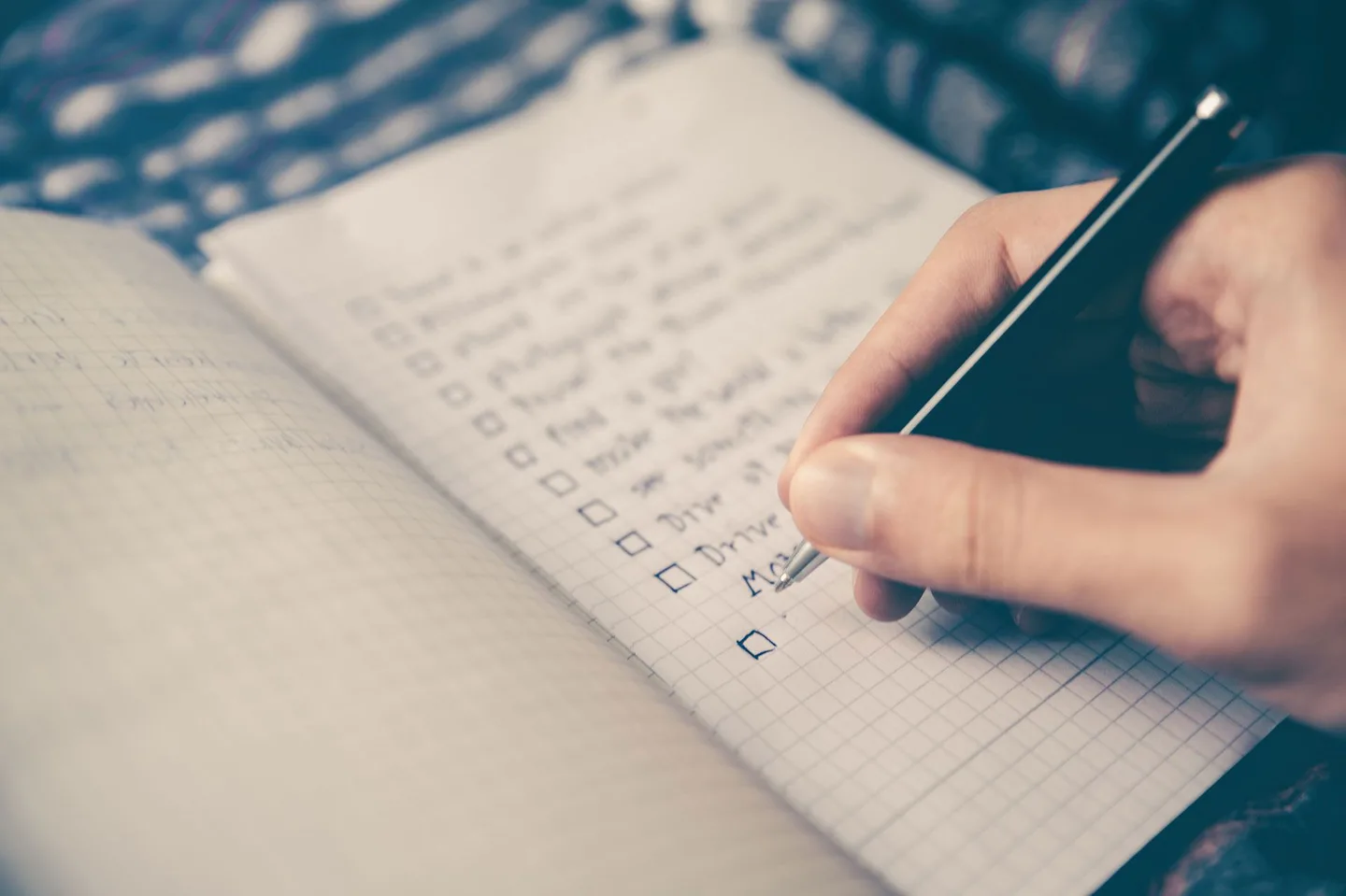 A hand taking notes and setting priorities in a notebook.